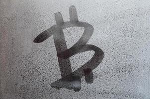 The bitcoin symbol on the misted sweaty glass. Abstract background image. Cryptocurrency concept photo