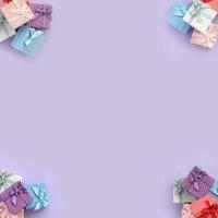 Piles of a small colored gift boxes with ribbons lies on a violet background. Minimalism flat lay top view pattern photo