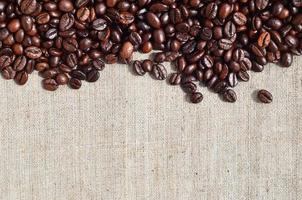 Texture of a gray canvas made of old and coarse burlap with coffee beans on it photo