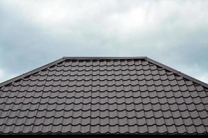 Brown roof tiles or shingles on house as background image. New overlapping brown classic style roofing material texture pattern on a actual house photo