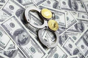 Police handcuffs and bitcoins lie on a large number of dollar bills. The concept of problems with the law during the illegal cryptocurrency mining and bitcoin operations photo