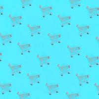 Shopping addiction, shopping lover or shopaholic concept. Many small empty shopping carts perform a pattern on a pastel colored paper background. Flat lay composition, top view photo