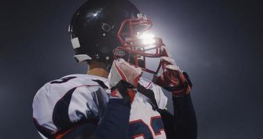 American Football Player Putting On Helmet on large stadium with lights in background photo