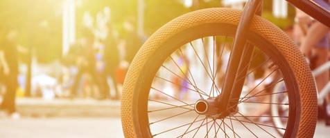 A BMX bike wheel against the backdrop of a blurred street with cycling riders. Extreme Sports Concept photo