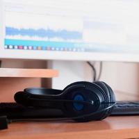 Big black headphones lie on the wooden desktop of the sound designer photo