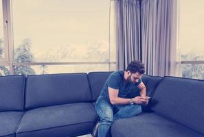 joven casual usando un teléfono móvil en casa foto