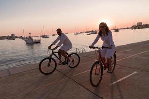 familia feliz disfrutando juntos de una hermosa mañana junto al mar, padres montando en bicicleta y su hijo montando una scooter eléctrica. enfoque selectivo foto