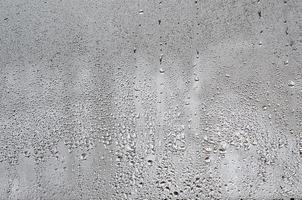 Texture of a drop of rain on a glass wet transparent background. Toned in grey color photo