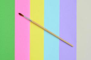 A new paint brush lie on texture background of fashion pastel pink, blue, green, yellow, violet and beige colors paper in minimal concept. Abstract trendy pattern photo