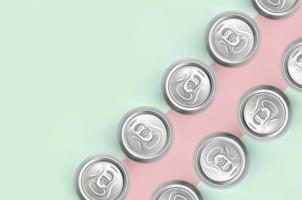 Many metallic beer cans on texture background of fashion pastel turquoise and pink colors photo