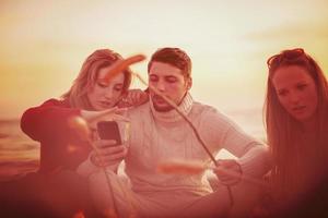 grupo de jóvenes amigos sentados junto al fuego en la playa foto