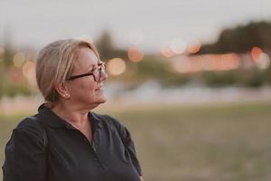 Portrait of an elderly woman with blonde hair and glasses on the beaches of the Mediterranean Sea at sunset. Selective focus photo