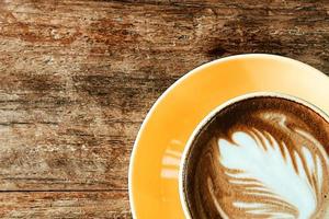 Top view of a latte art coffee on old wooden table. photo