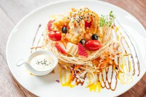 Fruits salad with salad sauce on wooden table photo