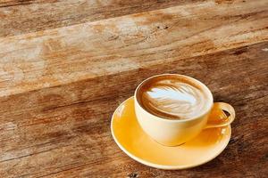 Top view of a latte art coffee on old wooden table. photo