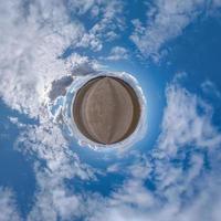 pequeño planeta en el cielo azul con hermosas nubes con transformación de panorama esférico de 360 grados. vista aérea abstracta esférica. curvatura del espacio. foto