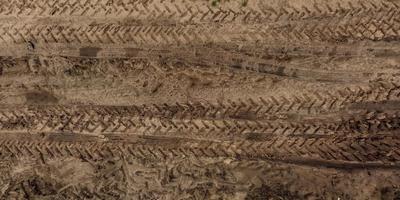 panorama of surface from above of gravel road with car tire tracks photo