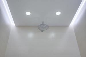 suspended ceiling with halogen spots lamps and drywall construction in bathroom with shower head photo