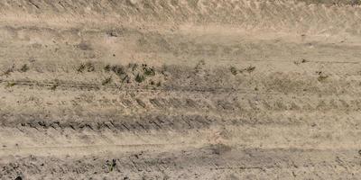 panorama of surface from above of gravel road with car tire tracks photo