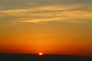 amanecer en la orilla del mar muerto en israel. el sol sale por detrás de las montañas en jordania. foto