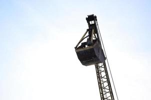 Old yellow mechanical clamshell grab on blue sky background photo