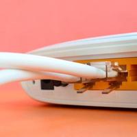 The Internet cable plugs are connected to the Internet router, which lies on a bright orange background. Items required for Internet connection photo