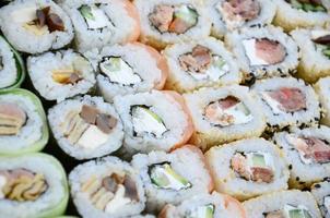 Close-up of a lot of sushi rolls with different fillings. Macro shot of cooked classic Japanese food. Background image photo