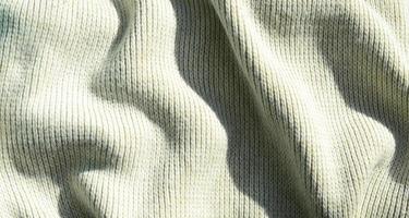 textura de tela de un suéter de punto amarillo suave. imagen macro de la estructura de enlaces en hilos foto
