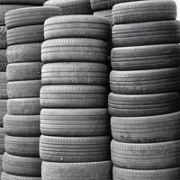 Old used tires stacked with high piles in secondary car parts shop garage photo