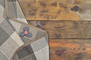 A rare wooden handmade spinner lies on a checkered plaid on a brown wooden background surface. Trendy stress relieving toy photo