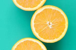 Top view of a several orange fruit slices on bright background in turquoise green color. A saturated citrus texture image photo