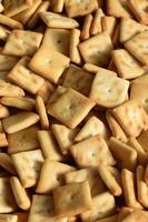 Background texture of small edible squares baked from dough and sprinkled with salt. A lot of salt cracker photo