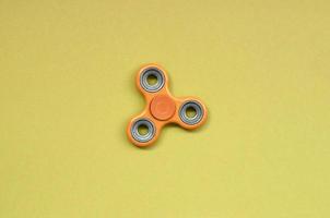 orange fidget spinner lies on texture background of fashion pastel orange color paper photo