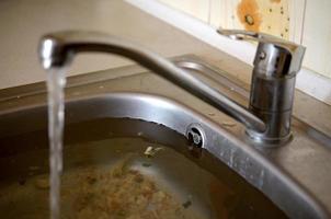 Stainless steel sink plug hole close up full of water and particles of food photo