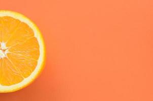 Top view of a one orange fruit slice on bright background in orange color. A saturated citrus texture image photo