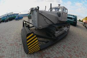 Photo of a gray bulldozer among the railway trains. Strong distortion from the fisheye lens