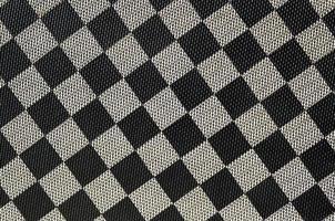 Plastic texture in the form of a very small cloth binding, painted in black and gray in the style of a chessboard. Macro shot photo