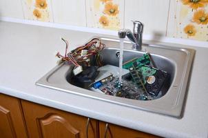 Hardware in kitchen sink under the water flow computer cleaning metaphoric concept photo