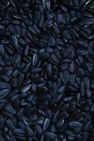 A pattern of many unprocessed fried sunflower seeds in a black shell. photo