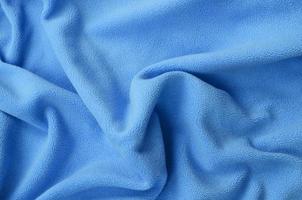 The blanket of furry blue fleece fabric. A background of light blue soft plush fleece material with a lot of relief folds photo