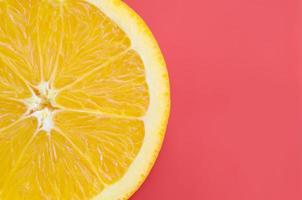 Top view of a one orange fruit slice on bright background in red color. A saturated citrus texture image photo