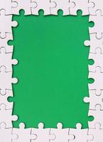 Framing in the form of a rectangle, made of a white jigsaw puzzle around the green space photo