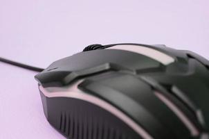 Closeup of a black gaming optical mouse on a pink background photo