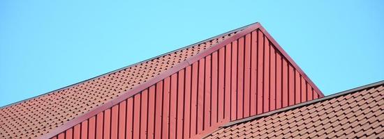 A fragment of a roof from a metal tile of dark red color. Quality Roofing photo