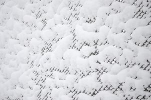 Close-up metal mesh covered with a thick layer of snow in the cells photo