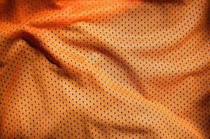 fondo de textura de tela de ropa deportiva naranja. vista superior de la superficie textil de tela naranja. camiseta de baloncesto brillante. espacio de texto foto