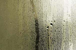 Texture of a drop of rain on a glass wet transparent background. Toned in yellow color photo