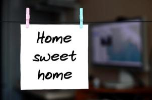 Home sweet home. Note is written on a white sticker that hangs with a clothespin on a rope on a background of office interior photo