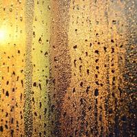 The texture of misted glass with a lot of drops and drips of condensation against the sunlight at dawn. Background image photo