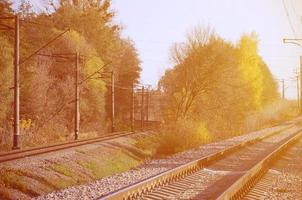 paisaje industrial de otoño. ferrocarril retrocediendo en la distancia entre árboles de otoño verdes y amarillos foto